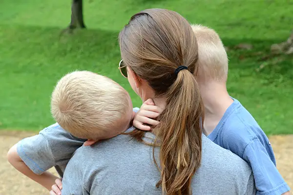 A mother holding and comforting her small twin boys after recovering from a case of Parent Alienation.