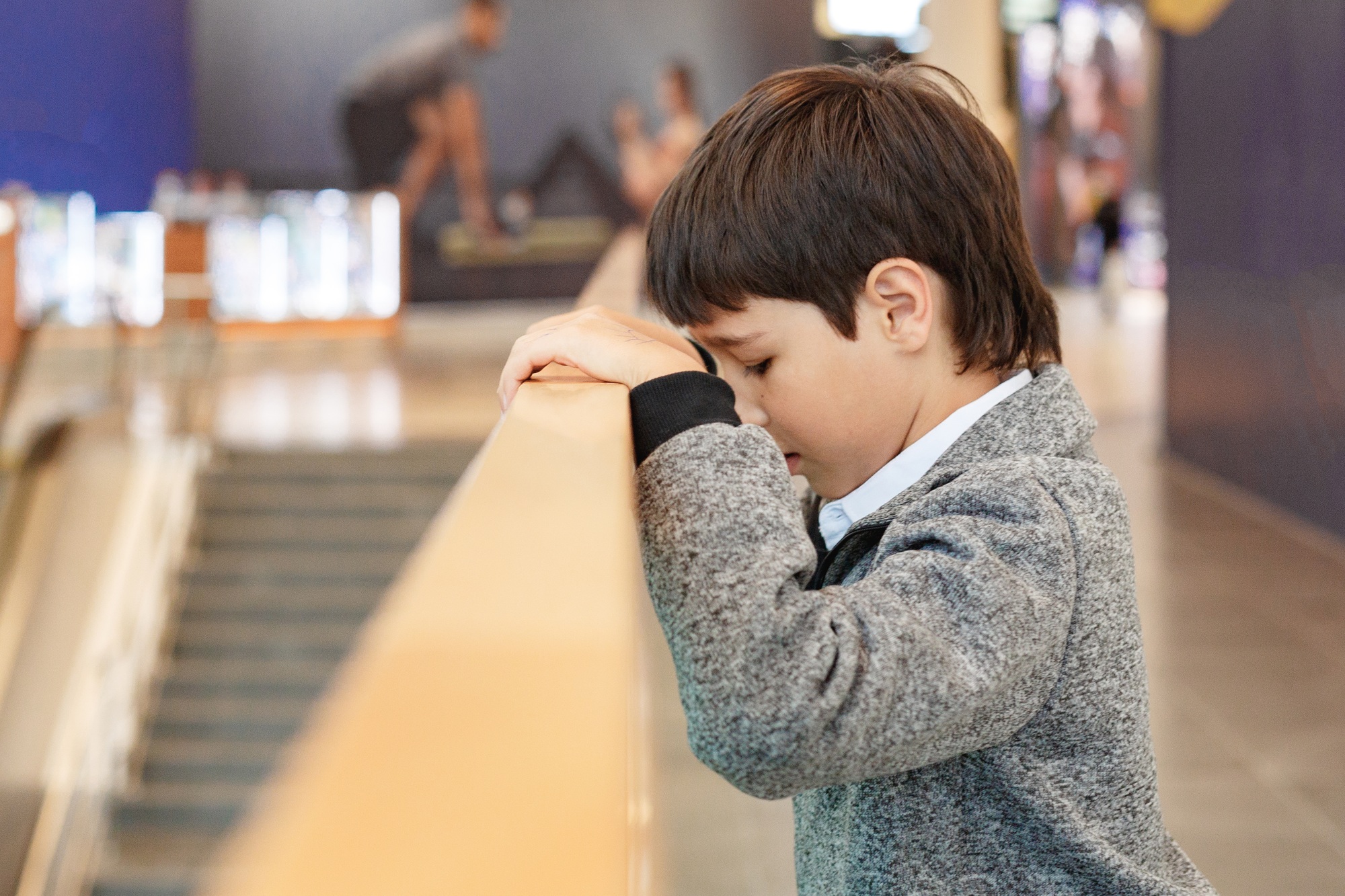 Sad Belton Texas boy standing near elevator in shopping mall